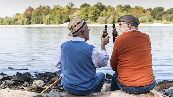 Zwei ältere Männer trinken ihr Bier am Fluss
