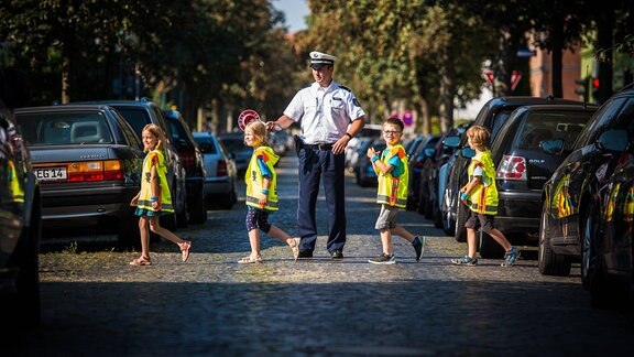 So ist es ganz sicher: Bei einer ADAC-Aktion zum Schulanfang an einer Grundschule in Erfurt sichert ein Polizist die Straße ab. 