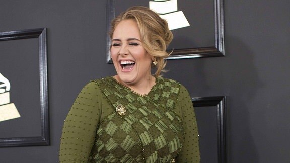 Adele bei den Grammy Awards 2017 trägt ein grünes Kleid und lacht.
