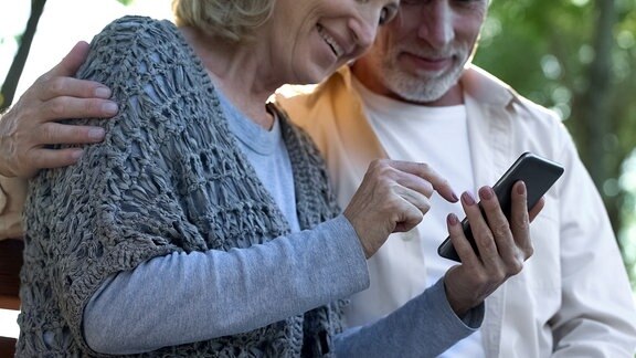 Zwei ältere Menschen bedienen gemeinsam ein Smartphone