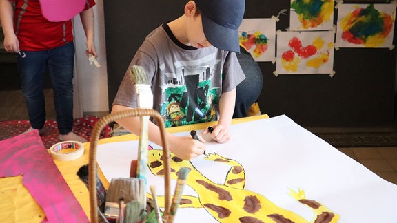 Junge malt Plakat zur Aktionswoche Kinder aus Suchtfamilien
