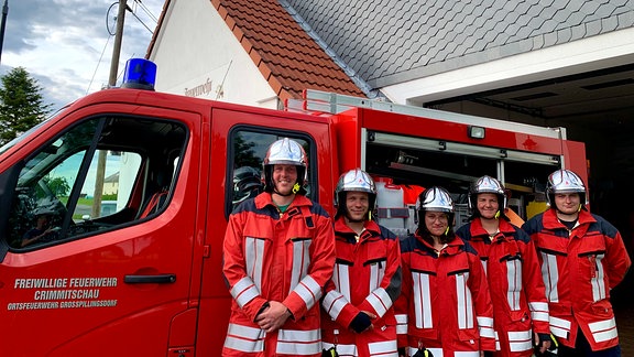 Fünf Feuerwehrleute der Freiwilligen Feuerwehr in Großpillingsdorf stehen vor einem Feuerwehrwagen