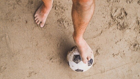 Ein nackter Fuß auf einem Fußball
