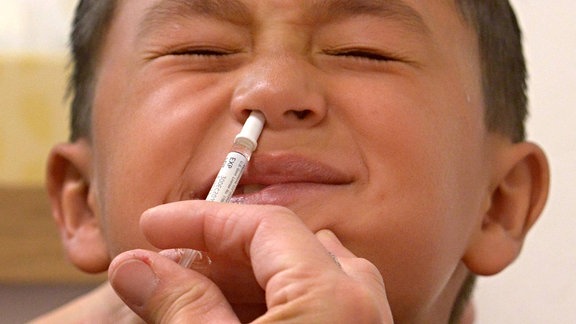 Ein Erstklässler reagiert nach einer Impfung gegen Grippe mit Nasenspray