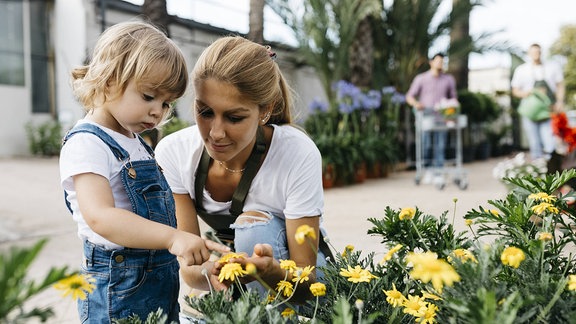 Eine junge Frau zeigt einem kleinen Mädchen Blumen