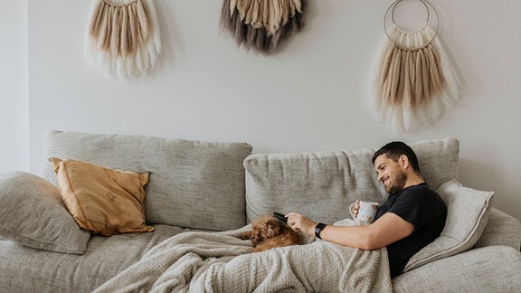 Mann mit Hund auf der Couch