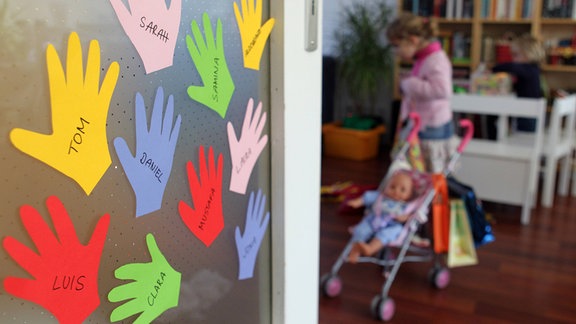Bunte, gebastelte Hände mit Namen der Kinder hängen an einer Tür.