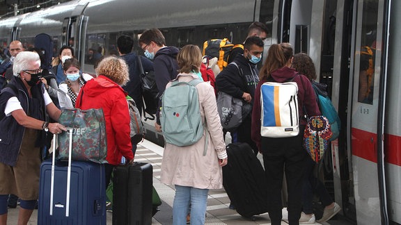 Reisende mit Mund-Nasen-Schutz vor dem Einsteigen in einen Zug in Frankfurt/Main