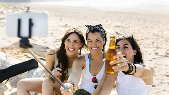 Freunde nehmen mit dem Selfie-Stick ein Foto am Strand auf