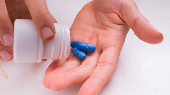 Person schüttet Tabletten aus einer Dose in die Hand