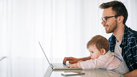 Vater mit Baby am Laptop (Symbolfoto)