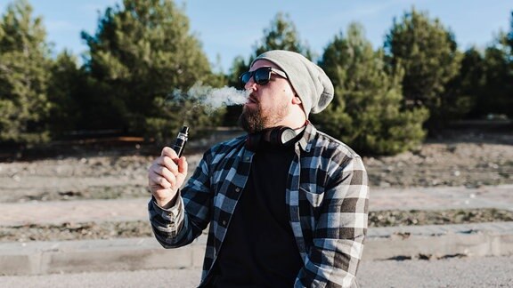 Mann mit E-Zigarette mit Liquid (Symbolfoto)